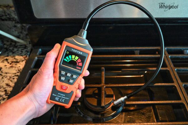 Customer using natural gas leak detector to check for a leak in their gas stove.